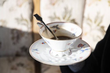 Güneşli terasta yarı sarhoş kahveli klasik kahve fincanı ve çay tabağı. Nostaljik sabah atmosferi.