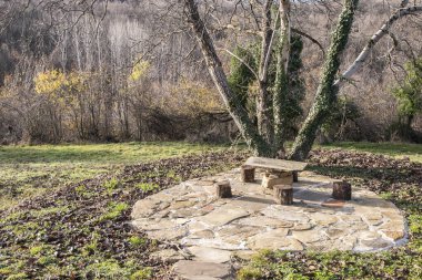 Dağlık villa bahçesinde masası ve taburesi olan taşralı bir yerleşim yeri. Huzurlu bir kış manzarası.