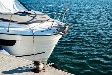 Sakin liman suyuna demirlemiş motorlu yat pruvasının yakın görüntüsü lüks bir tekneyi, seyahat tarzını ve deniz zevkini temsil ediyor..