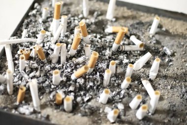 Halka açık kül tablası sigara izmaritleri ve küllerle dolup taşıyor. Sigara bağımlılığı, sağlıksız yaşam tarzı, nikotin bağımlılığı, umumi sigara içme alanları ve tütün kirliliği kavramı.