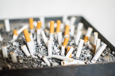 Halka açık kül tablası sigara izmaritleri ve küllerle dolup taşıyor. Sigara bağımlılığı, sağlıksız yaşam tarzı, nikotin bağımlılığı, umumi sigara içme alanları ve tütün kirliliği kavramı.