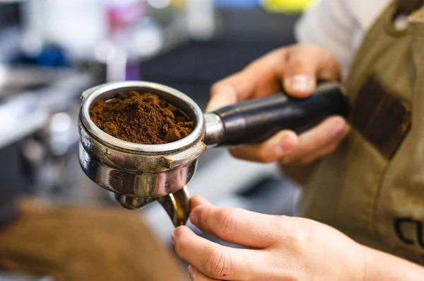 Primo piano della mano barista femminile che tiene il caffè macinato per preparare l'espresso. — Foto Stock