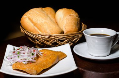 Peru kahvaltısı, Peru usulü soğan soslu tamale, ekmek ve masada bir fincan kahve..