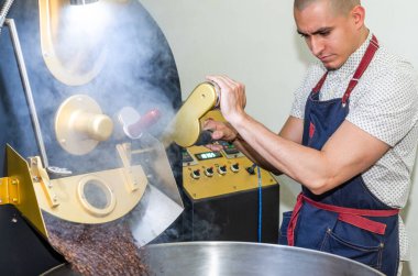 İnsanlar kahve aromalı kahve çekirdeklerini fırında pişirmek için kullanılan modern bir makinenin üzerinde kızartıyorlar..
