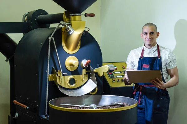 Mans manos tostado café granos de café aromáticos sobre una máquina moderna utilizada para asar frijoles. — Foto de Stock