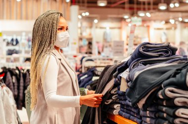 Yüzünde antivirüs maskesi ve örgüleri olan güzel bir kadın. Moda, güzellik ve alışveriş endüstrisinde virüs koruma kavramı.