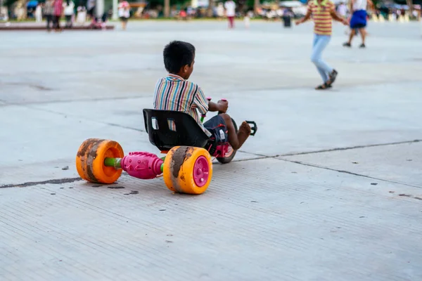 Chico irreconocible con la espalda vuelta en el parque conduciendo un coche de juguete antes de la pandemia. — Foto de Stock