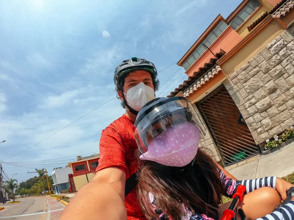 Pai e filha andando de bicicleta juntos ao ar livre em tempos de coronavírus. — Fotografia de Stock