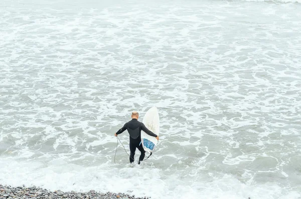 Portret dojrzałego surfera stojącego na plaży z deską surfingową w rękach. — Zdjęcie stockowe