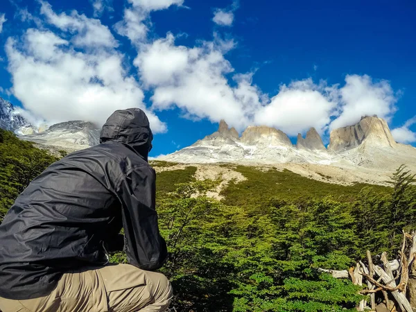 Člověk zezadu, sedící na kameni a dívající se na čisté hory, Torres del Paine. — Stock fotografie