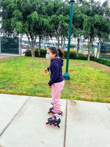 Niña caucásica de 8 años montando patines sobre ruedas en la carretera en el parque. Estilo de vida infantil saludable. — Foto de Stock