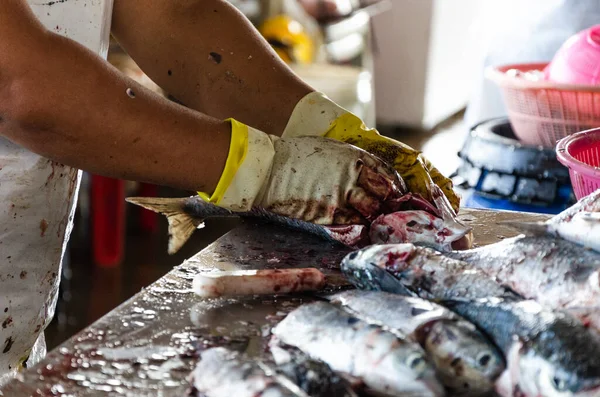 Mans hand med handskar förbereder fisk för försäljning på marknaden. — Stockfoto