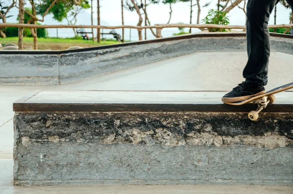 Skateboarder está fazendo um truque de moagem torto em um banco no skatepark. — Fotografia de Stock