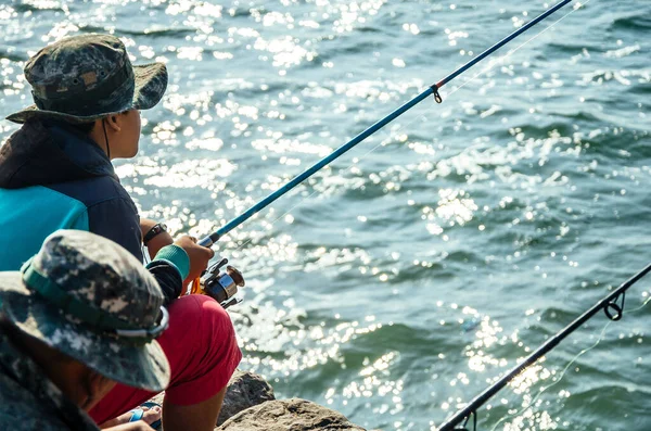 Pescatore seduto con una canna da pesca in mare, pesca. — Foto Stock
