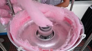 Satıcı sokak makinesinde pembe pamuk helva pamuk şeker yapıyor.