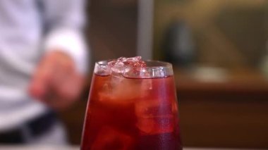 Barmen tezgahtaki kırmızı kokteyle kurutulmuş narenciye garnitürü ekliyor. Kokteyl hazırlığında son dekoratif dokunuş.