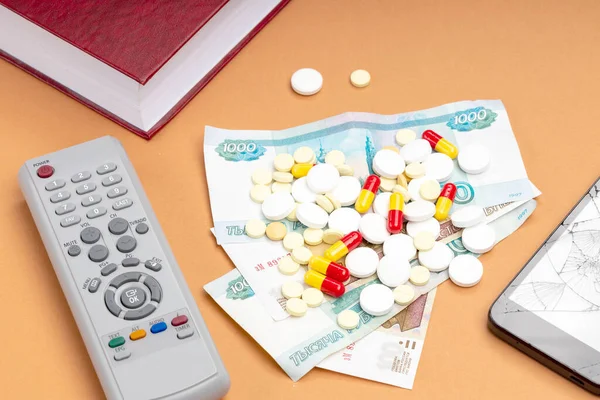tablets and money with a TV remote control. getting sick is expensive and takes a long time