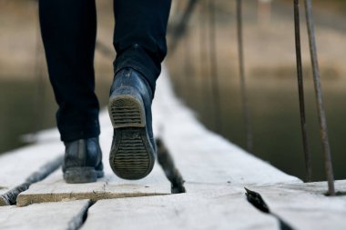 Tahta bir asma köprüye düz olmayan kalaslarla bas. tehlikeli yürüme alanı