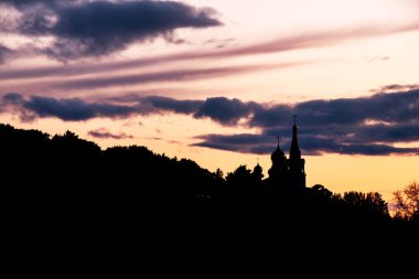 Dağda, günbatımının arka planında bir Ortodoks kilisesinin silueti. akşam gökyüzü