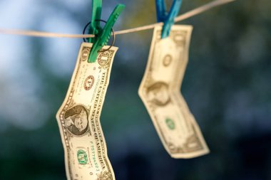 Kururken ipe asılı duran iki dolar, ıslandıktan sonra para kurutma kavramı.