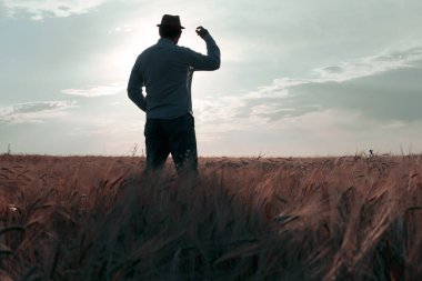 Şafak vakti şapkalı bir adam sahada sırtı bize dönük duruyor. Yeni bir gün için geleceğe bakmak.