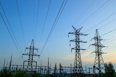 Akşamları gökyüzüne karşı birçok elektrik hattı, direkler ve kablolar.