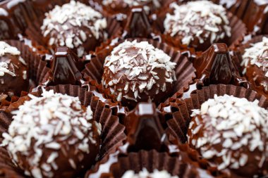 Plastik ambalajlı yuvarlak çikolatalı şekerler, aynı hindistan cevizi serpiştirilmiş şekerler arasında.