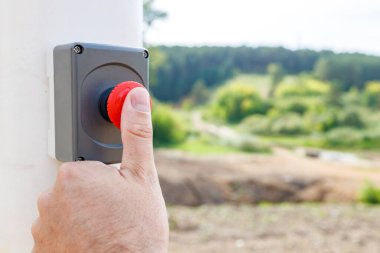 Bir adamın eli dışarıdaki desteğin kırmızı düğmesine basar. Kaza ya da yangın ihbarı