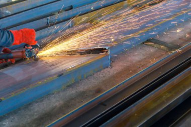 Elinde öğütücü olan eller metal bir kiriş görmüş. Metal bir parçayı kesme işlemi.