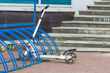 Motosiklet parkındaki sıradan beyaz tekerlekli bir scooter sokakta. scooter depolama sistemi