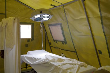 a lamp above the surgical table in a tent military field hospital and a screen. reenactment of a WWII hospital
