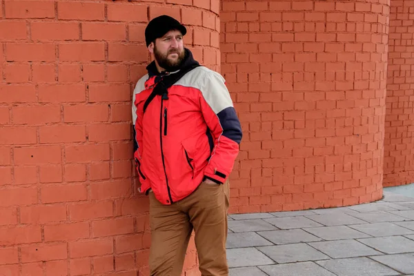 Bearded Man Stands His Back Brick Wall Looks Hands Jeans — Stock Photo, Image