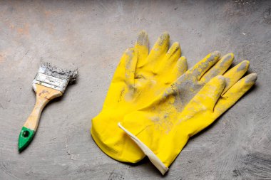 Ressamın vurduğu ve gri bir tuvale koyduğu aletler. eldiven ve fırça