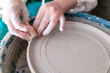 Çemberin etrafında dönen büyük bir tabak oluştururken çömlekçinin ellerine yakın plan. bir tabak oluşturma süreci