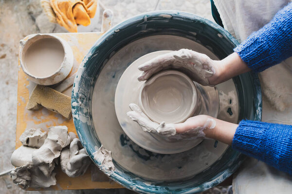 top view of the hands of a potter in the process of working on a circle. raw clay. making a clay cup by hand
