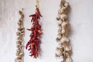 Duvarda bir yığın biber ve sarımsak asılı. Geleneksel yollarla sarımsak ve biber depoluyor.