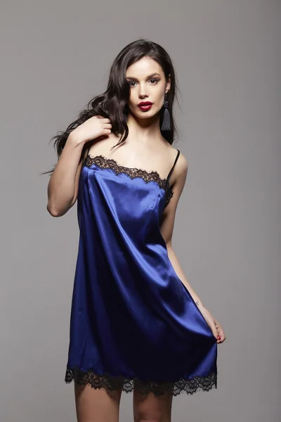 Sexy mujer morena de moda con pelo largo oscuro y labios rojos en vestido de noche azul con encaje y pendientes negros —  Fotos de Stock
