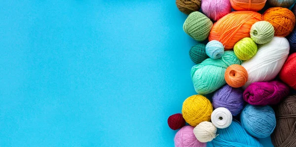 Düz örgü. Mavi arka planda çeşitli renkli iplikler. Metin için boşluk