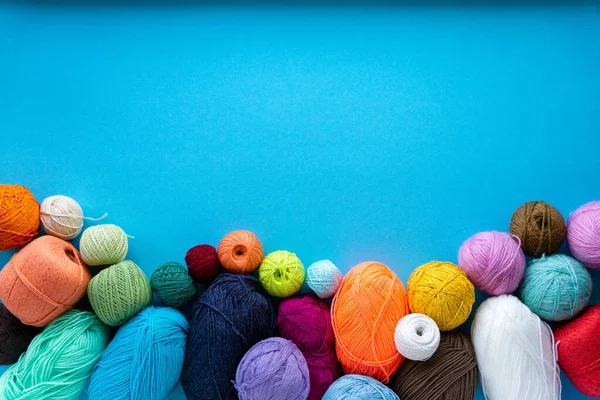 Düz örgü. Mavi arka planda çeşitli renkli iplikler. Metin için boşluk