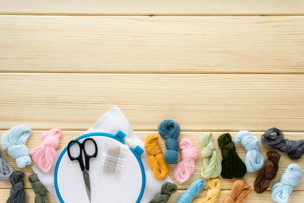 Nakış işlemek için düz eşyalar. Ahşap bir arka planda diş ipliği, iğne ve tuval, metin için boşluk