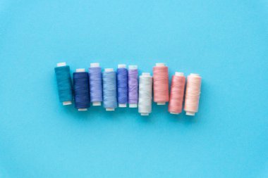 Renkli arkaplanda dikmek için mavi ve pembe iplikler kümesi, üst görünüm