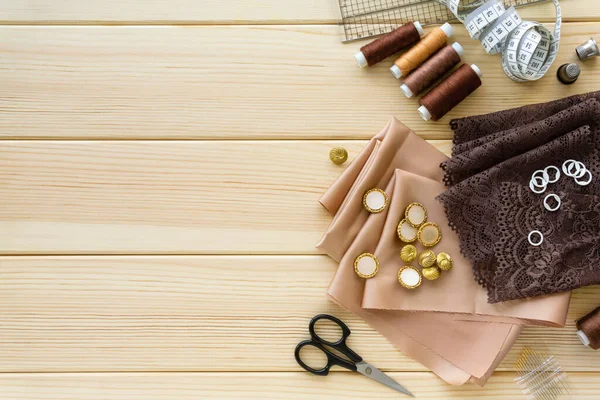 Düz dikiş aksesuarları. Ahşap arkaplanda kumaş, iplik ve terzilik araçları, metin için boşluk