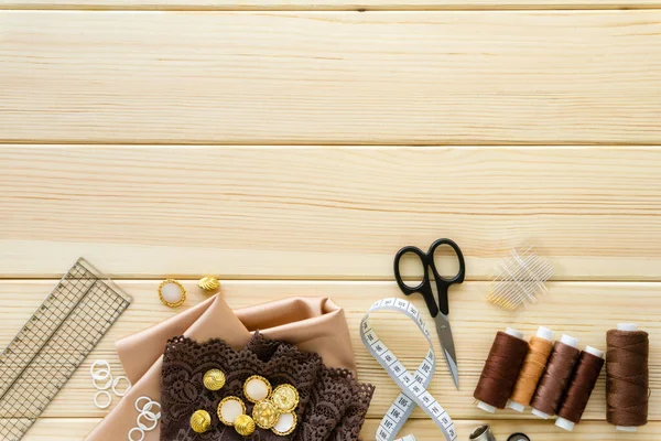 Düz dikiş aksesuarları. Ahşap arkaplanda kumaş, iplik ve terzilik araçları, metin için boşluk