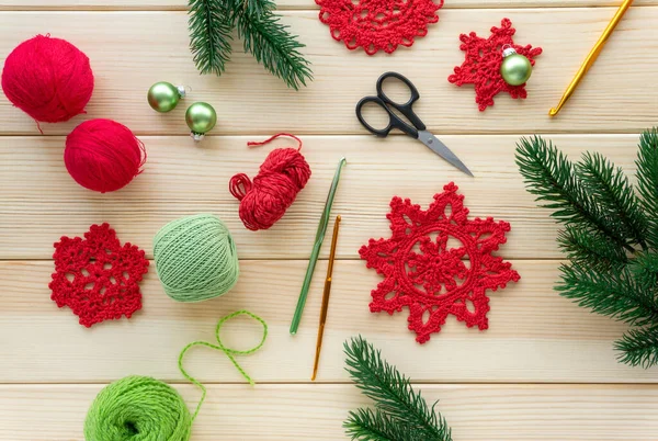 Christmas flat lay of items for needlework. Knitted snowflakes, threads and hooks on wooden background