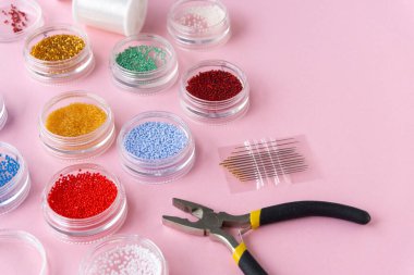 Yaratıcılık için malzemeler. Pembe arka planda boncuklar, olta ipi ve tel kesiciler