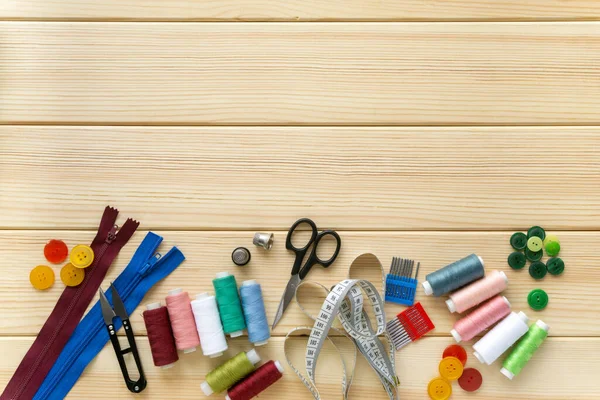 Terzi için düz aksesuarlar. Ahşap arka planda dikiş malzemeleri seti, metin için boşluk
