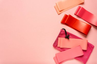 Renkli arkaplanda pembe fitness bantlarının düz yatışı, metin için boşluk