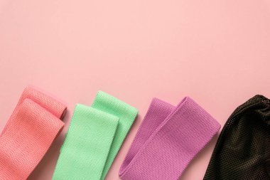 Pembe arka planda çok renkli kumaş fitness bantları.