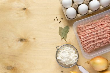 Hamur köftesi pişirmek için gerekli malzemeler. Ahşap arka planda kıyma, yumurta, un ve baharatlar, kopyalanmış alan