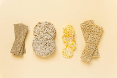 Various types of healthy crispbread on beige background, top view clipart